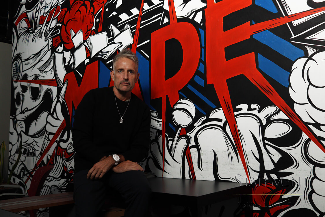 Cristian Rocha sentado frente a grafiti Made en su oficina