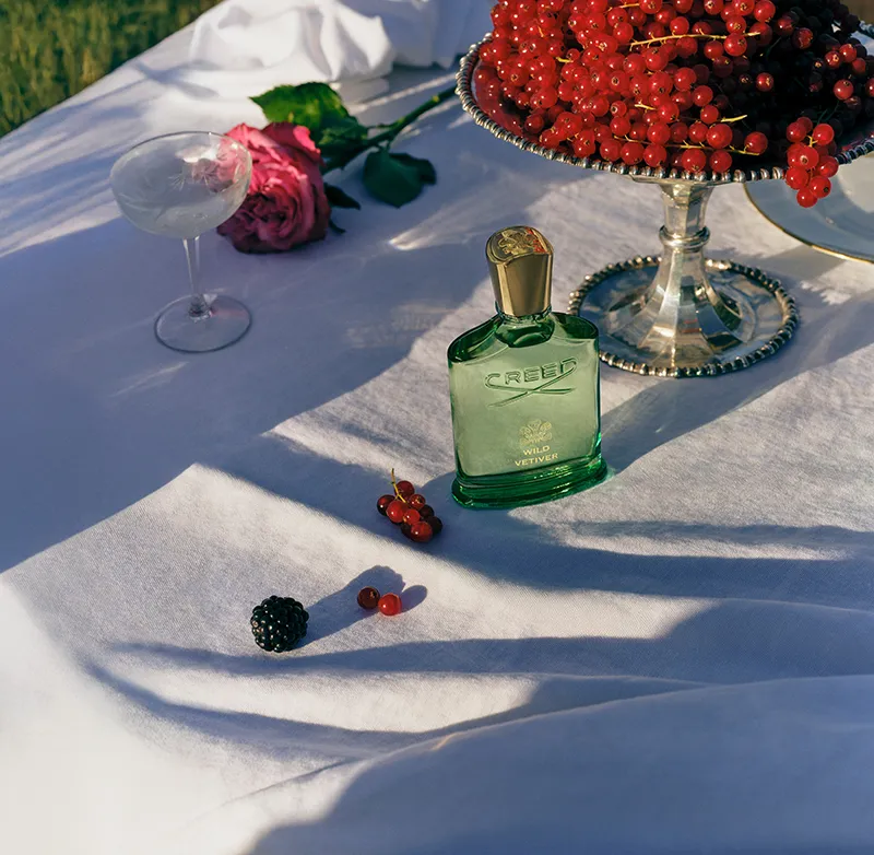 Perfume Creed Wild Vetiver, fragancia de lujo escena elegante con el perfume y elementos decorativos The House of Creed portada Statement